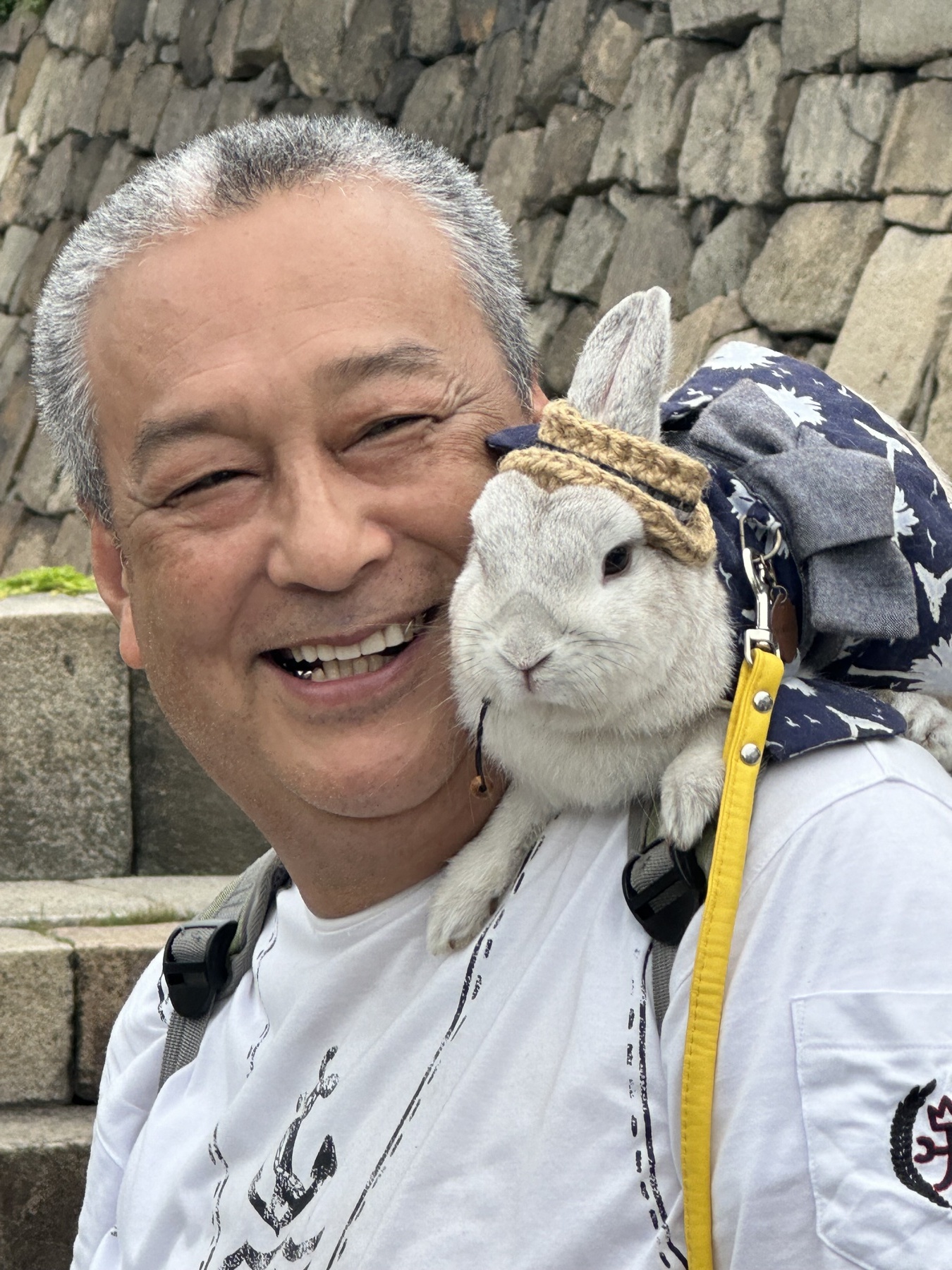 A smiling man carrying a white rabbit in Osaka